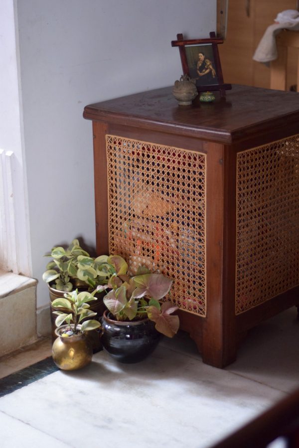 A cluster of plants in a beautiful planter besides a cane and teak dhobi bok